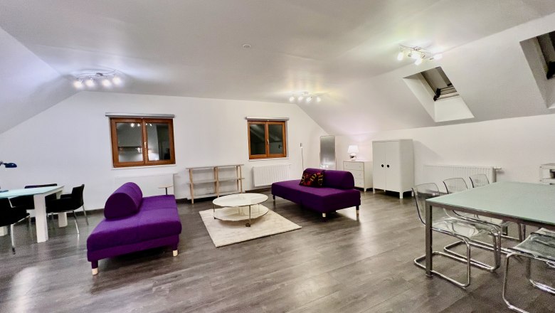 Loft am Hauptplatz, © Relax Apartments Modernes Loft mit violetten Sofas, Esstisch und Holzboden.