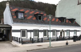 Hausansicht Ferienwohnung Rosengarten, © Familie Mitra Ansicht eines weißen Hauses mit schwarzem Zaun und Dachfenstern.