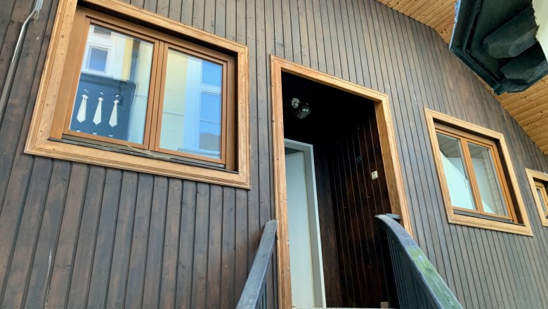 Hausansicht, © Relax Apartments Nahaufnahme einer Hausfassade mit Holzwand und Fenstern.