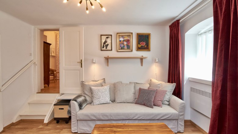 Gemütliches Wohnzimmer mit Sofa, Holztisch, Teppich und Wandbildern.