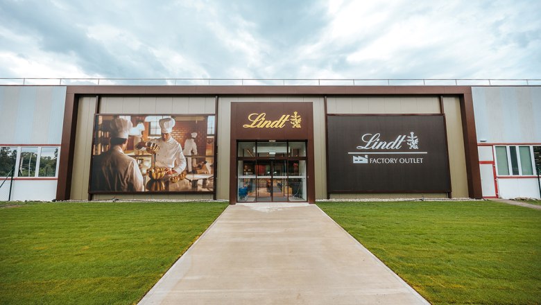 Eingang des Lindt Factory Outlet mit großen Werbebannern.