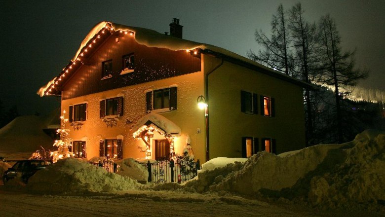 Haus Kohl im Winter, © Tourismusbüro Semmering Ein beleuchtetes Haus im Schnee bei Nacht, umgeben von hohen Schneehaufen.