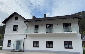 Zweist&ouml;ckiges wei&szlig;es Haus mit Balkon und blauen Himmel im Hintergrund.