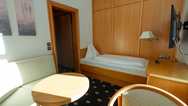 Einzelzimmer mit Bett, Sofa, Tisch und Fernseher.