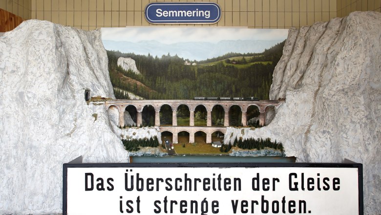 Modell des Kalte Rinne-Viadukts mit Zug und Landschaft im Hintergrund. Schild mit Aufschrift: 'Das Überschreiten der Gleise ist streng verboten.'