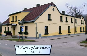 Gelbes Gebäude mit rotem Dach und Schild 'Privatzimmer G. Rath'.