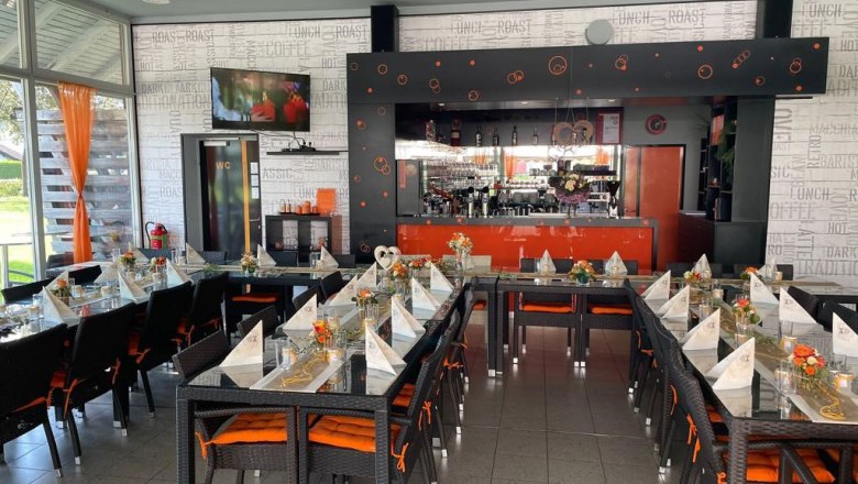 Ein stilvoll eingerichtetes Caf&eacute; mit gedeckten Tischen und einer Bar im Hintergrund.