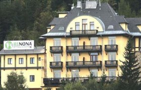 Gelbes Gebäude mit Balkonen und Schild 'Renona Rehabilitation'.