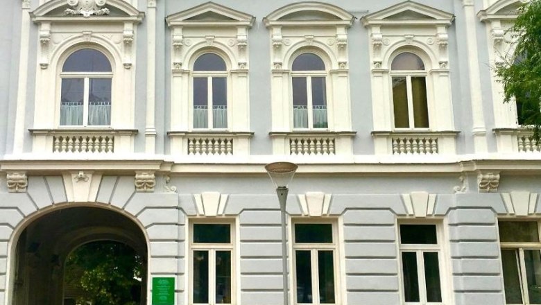 Loft am Hauptplatz, © Stadt Gloggnitz Historisches Gebäude mit verzierten Fenstern und einem Torbogen.