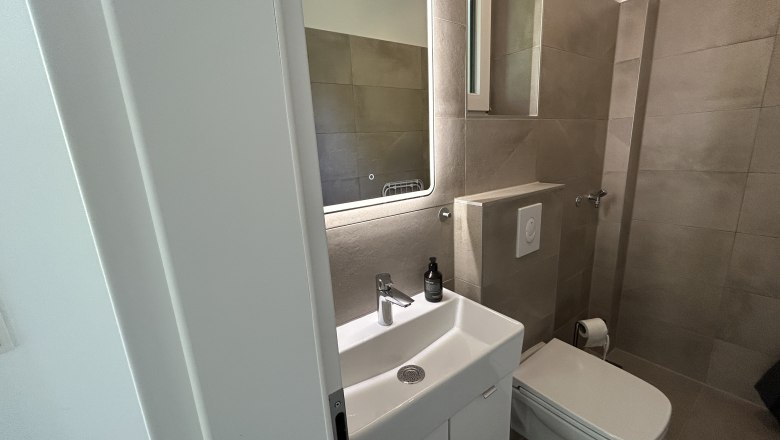 Modernes Badezimmer mit Waschbecken, Spiegel und Toilette.