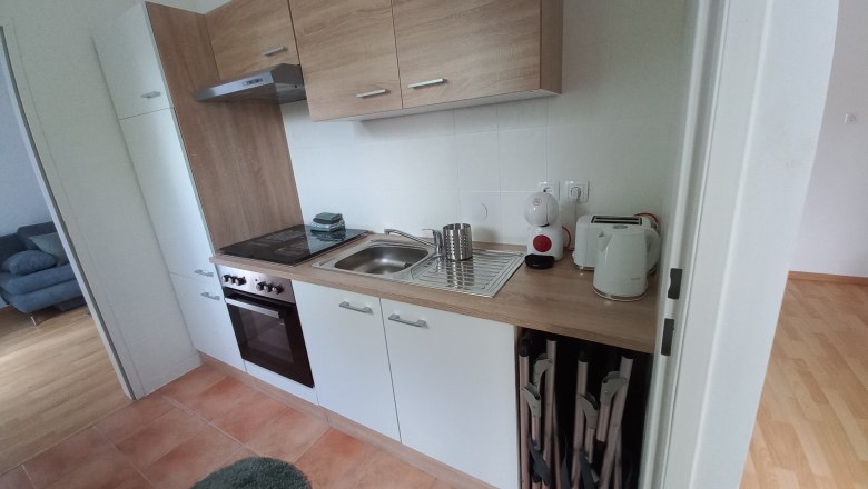 Moderne K&uuml;chenzeile mit Holz- und wei&szlig;en Elementen, Herd, Sp&uuml;le und K&uuml;chenger&auml;ten.