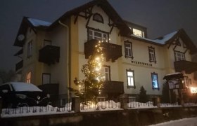 Ein beleuchtetes Gebäude im Schnee mit Weihnachtsdekoration.