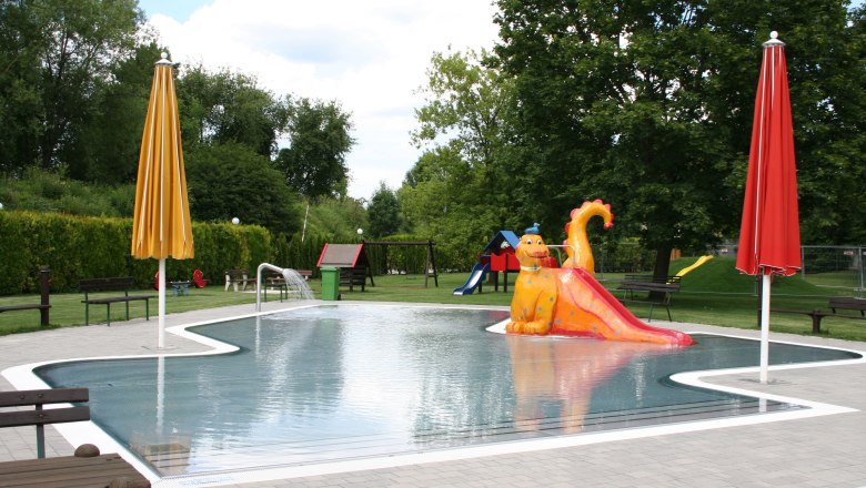 Kinderbecken mit Drachenrutsche und bunten Sonnenschirmen im Erholungszentrum Neunkirchen.