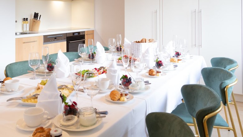 Eleganter Fr&uuml;hst&uuml;ckstisch in moderner K&uuml;che mit gedecktem Tisch, Geschirr und Speisen.