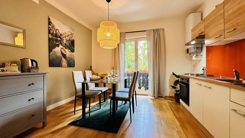 Gem&uuml;tliches Apartment mit Esstisch, St&uuml;hlen, K&uuml;chenzeile und Balkon.