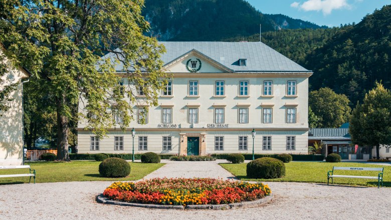 Schloss Reichenau mit Garten und Blumenbeet im Vordergrund.