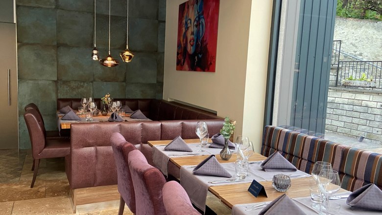 Elegantes Restaurant mit gedeckten Tischen und großen Fenstern.