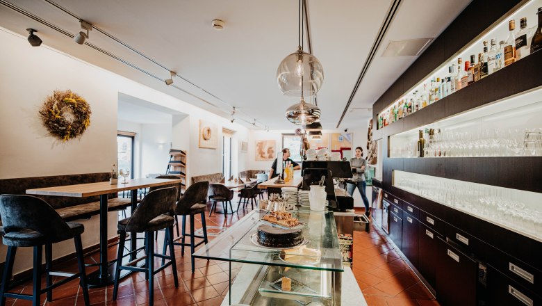 Innenansicht eines modernen Restaurants mit Bar, Tischen und St&uuml;hlen.