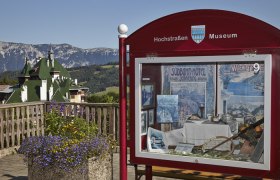 Schaukasten des Hochstraßenmuseums mit Berglandschaft im Hintergrund.