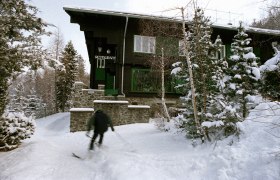 Ein Skifahrer fährt an einem verschneiten Gebäude vorbei, das als Restaurant dient.