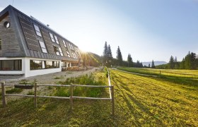 Naturfreundehaus Knofeleben in einer sonnigen Berglandschaft mit Solarpaneelen auf dem Dach.