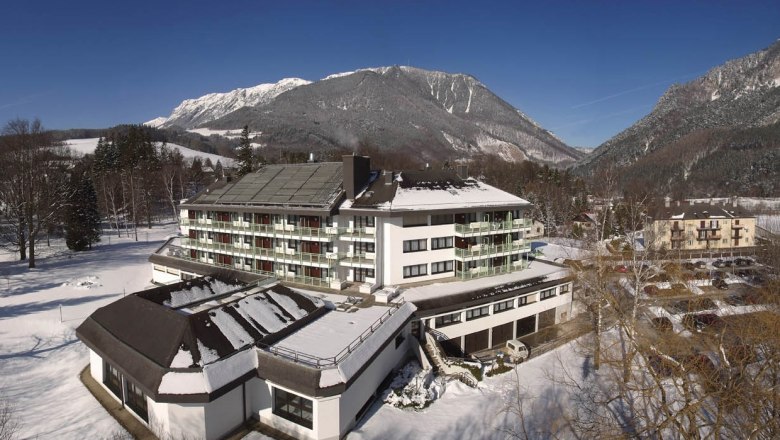 Parkhotel Hirschwang im Winter mit schneebedeckten Bergen im Hintergrund.