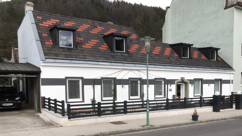 Hausansicht Ferienwohnung Rosengarten, © Familie Mitra Ansicht eines weißen Hauses mit schwarzem Zaun und Dachfenstern.