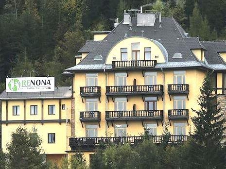 Gelbes Gebäude mit Balkonen und Schild 'Renona Rehabilitation'.