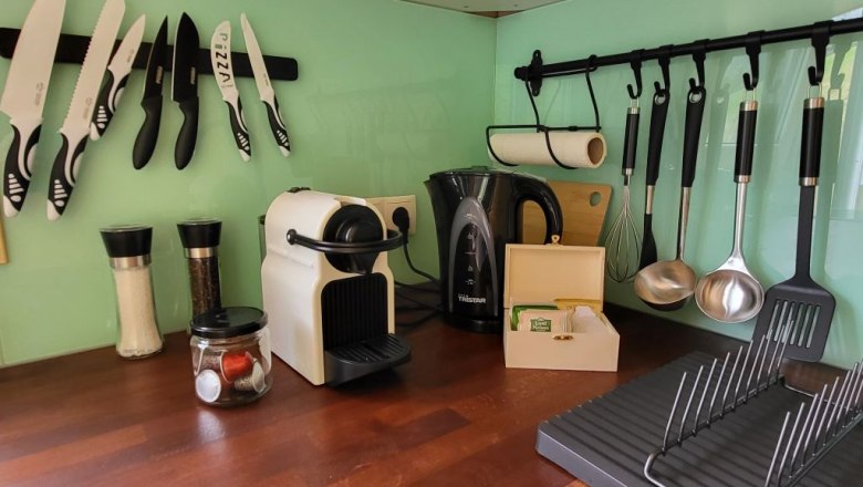 Küchenarbeitsplatte mit Kaffeemaschine, Wasserkocher, Gewürzmühlen und Küchenutensilien.