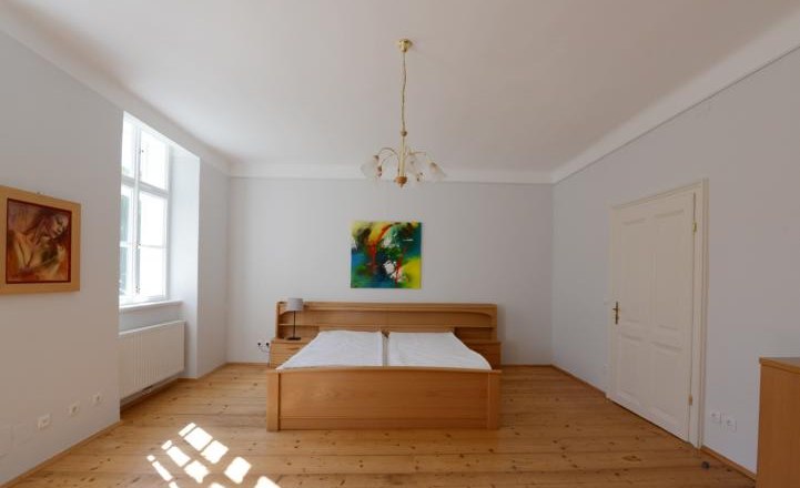 Schlafzimmer mit Holzboden, Doppelbett, zwei Gem&auml;lden und einem Fenster.