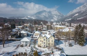 Verschneite Stadt mit Bergen im Hintergrund.