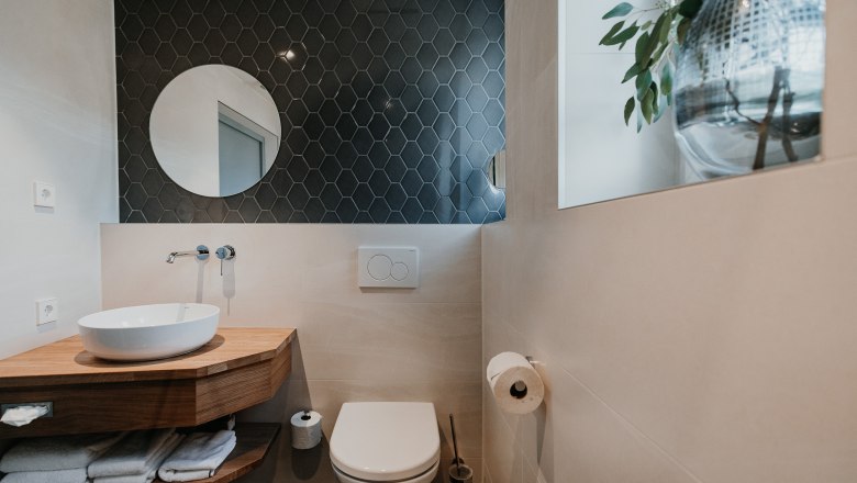 Modernes Badezimmer mit Waschbecken, Spiegel und Toilette.