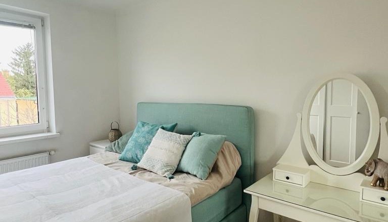 Schlafzimmer mit einem Bett, Kissen und einem Schminktisch mit Spiegel.