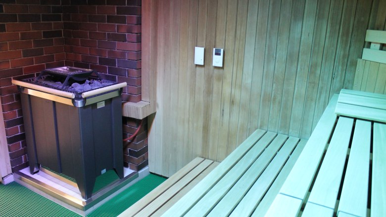 Innenansicht einer Sauna mit Holzverkleidung und Saunaofen.