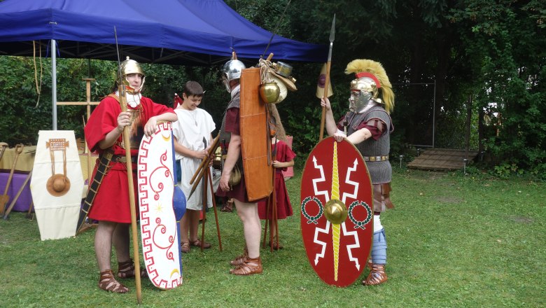 Personen in römischen Rüstungen bei einer historischen Nachstellung im Freien.