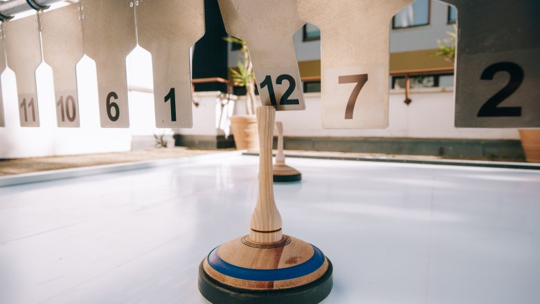 Eisstock auf einer glatten Fläche vor nummerierten Zielen.