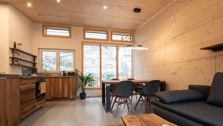 Moderner Wohn- und Essbereich mit Holzmöbeln und großen Fenstern.