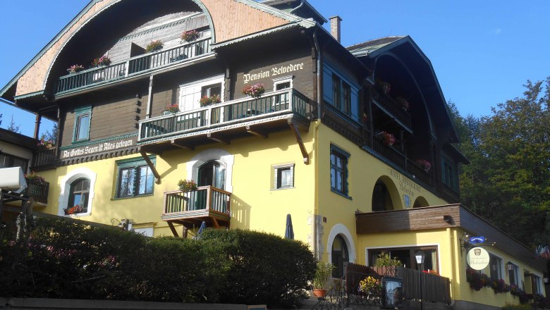 Hotel Belvedere, © Hotel Belvedere Ein traditionelles Hotel mit gelber Fassade und Holzbalkonen, dekoriert mit Blumen.