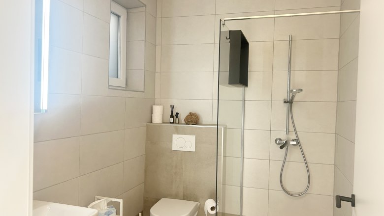 Modernes Badezimmer mit Dusche, Toilette und Waschbecken.