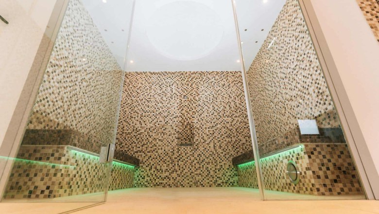 Moderner Saunabereich mit Mosaikfliesen und Glaswänden.