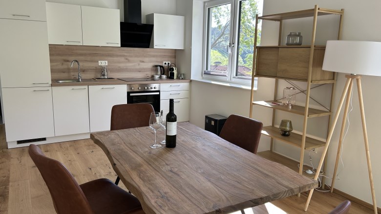 Moderne Küche mit Holztisch, Stühlen und Regal.