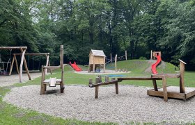 Spielplatz im Stadtpark mit Schaukeln, Rutsche und Klettergerüst.