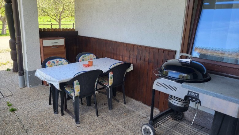 Terrasse mit Tisch, Stühlen und Grill.