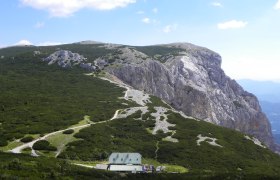 Berglandschaft mit Hütte und Wanderweg.