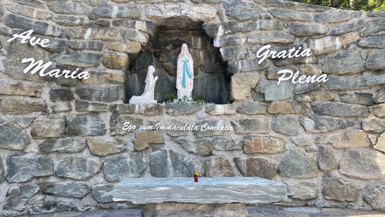 Steingrotte mit Marienstatue und Inschrift 'Ave Maria'.
