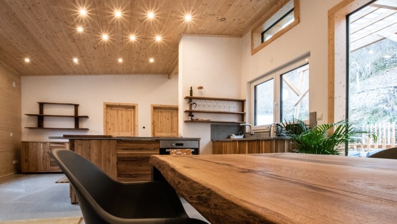 Moderner Wohnbereich mit Holzmöbeln und großen Fenstern.