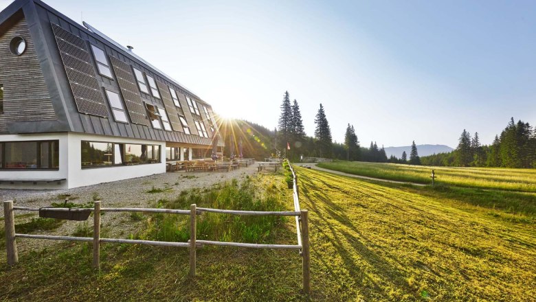 Naturfreundehaus Knofeleben am Gahns, © Wiener Alpen / Bene Croy Naturfreundehaus Knofeleben in einer sonnigen Berglandschaft mit Solarpaneelen auf dem Dach.