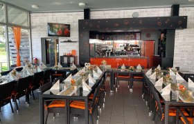 Ein stilvoll eingerichtetes Caf&eacute; mit gedeckten Tischen und einer Bar im Hintergrund.