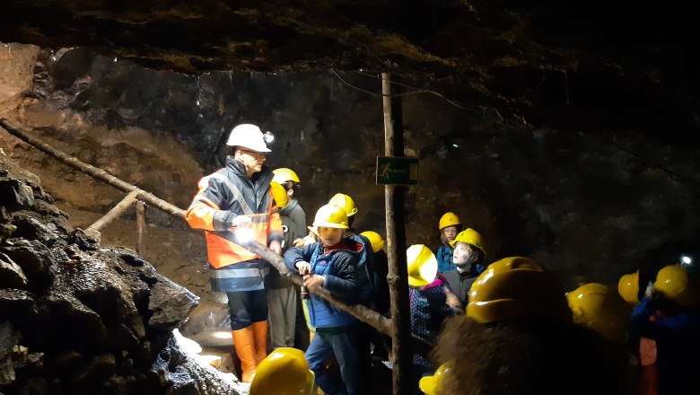 in einem Bergwerk erklärt ein Führer einer Kindergruppe etwas. Alle haben gelbe Helme auf