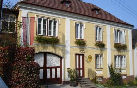 Gelbes Gebäude mit roten Fensterläden und Blumen, nostalgisches Postamt Küb.